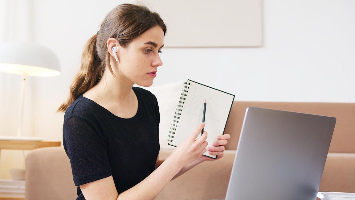 Young student with notebook attending online lesson